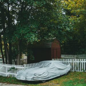 a car covered in a tarp sitting on the side of a road